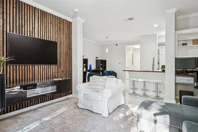 a living room with furniture a flat screen tv and a refrigerator