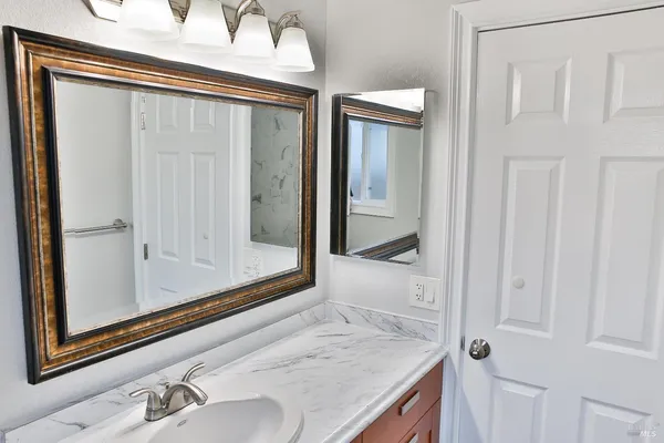 a bathroom with a granite countertop sink and mirror with bathtub
