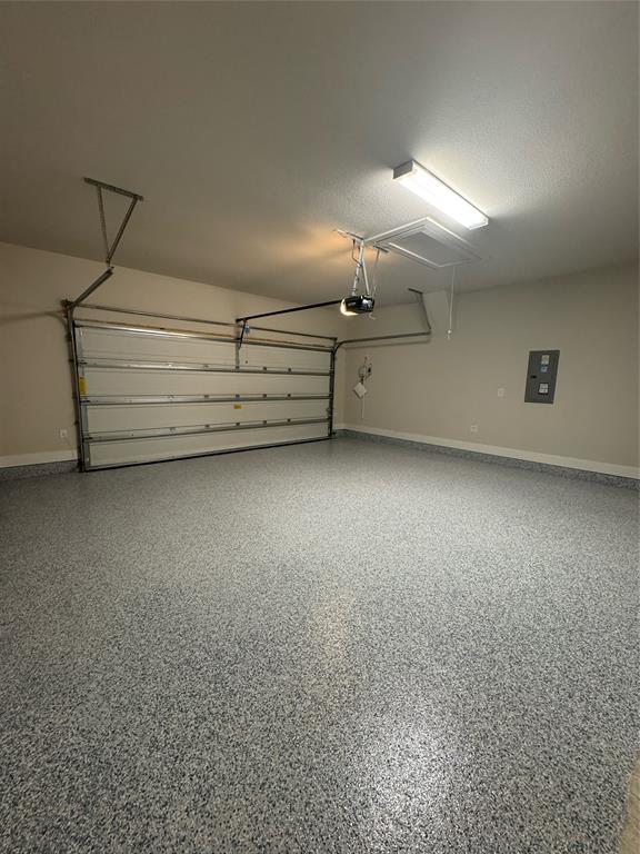 4123 Windy Point Court Oak Point, TX 75068 - Photo 28 of 29 Two-car garage featuring a speckled epoxy floor coating, an automatic overhead garage door opener, a white paneled garage door, and recessed lighting