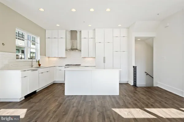 a large white kitchen with wooden floors and white appliances