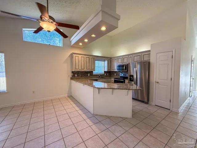 a kitchen with stainless steel appliances granite countertop a refrigerator and a stove top oven