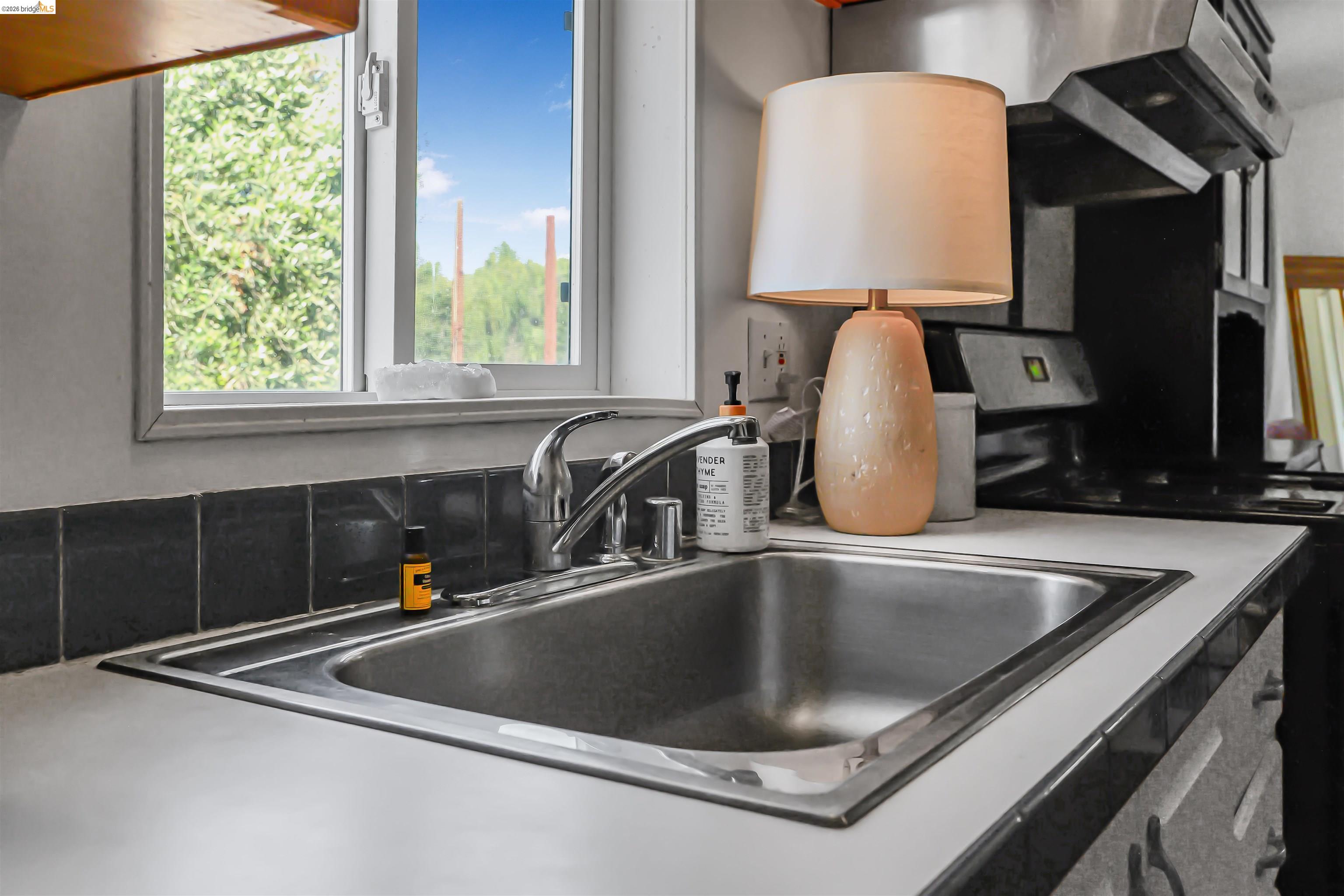 4419 Little John Road Copperopolis, CA 95228 - Photo 19 of 43 Stainless steel sink with a chrome faucet, set into a white countertop with a black tile backsplash