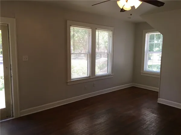 a view of an empty room with wooden floor and a window