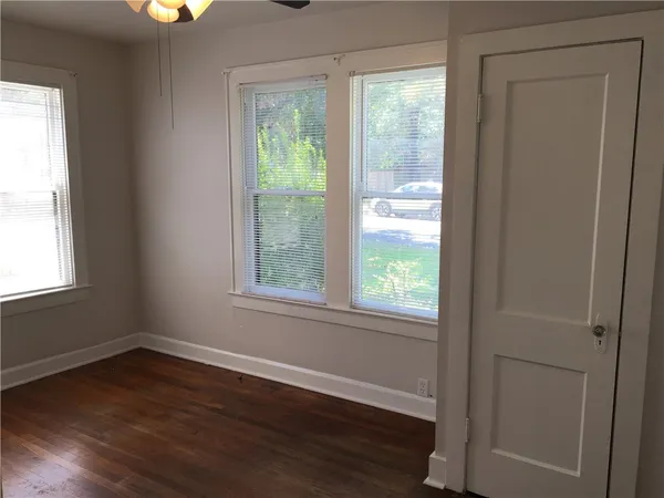 a view of an empty room with wooden floor and a window
