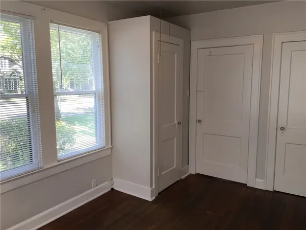 a view of an empty room with wooden floor and windows