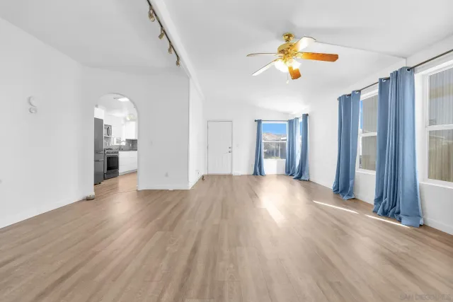 a view of an empty room with wooden floor and a window