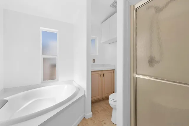 a spacious bathroom with a granite countertop toilet and a bathtub