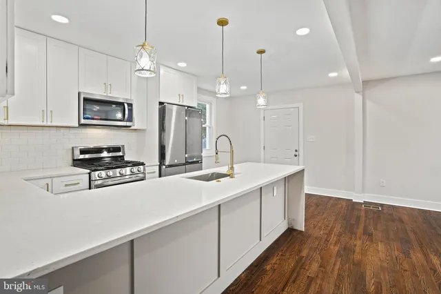 a kitchen with kitchen island a sink and a stove top oven with wooden floor