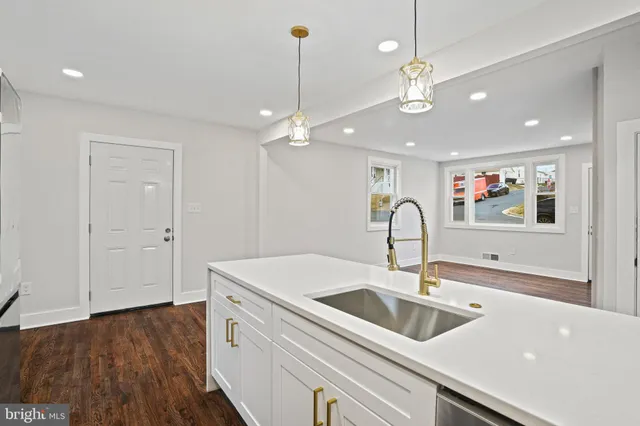 a kitchen with a sink and a stove with wooden floor