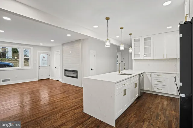 a large white kitchen with a stove a sink dishwasher and a refrigerator with wooden floor