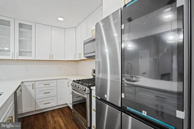 a kitchen with white cabinets and stainless steel appliances