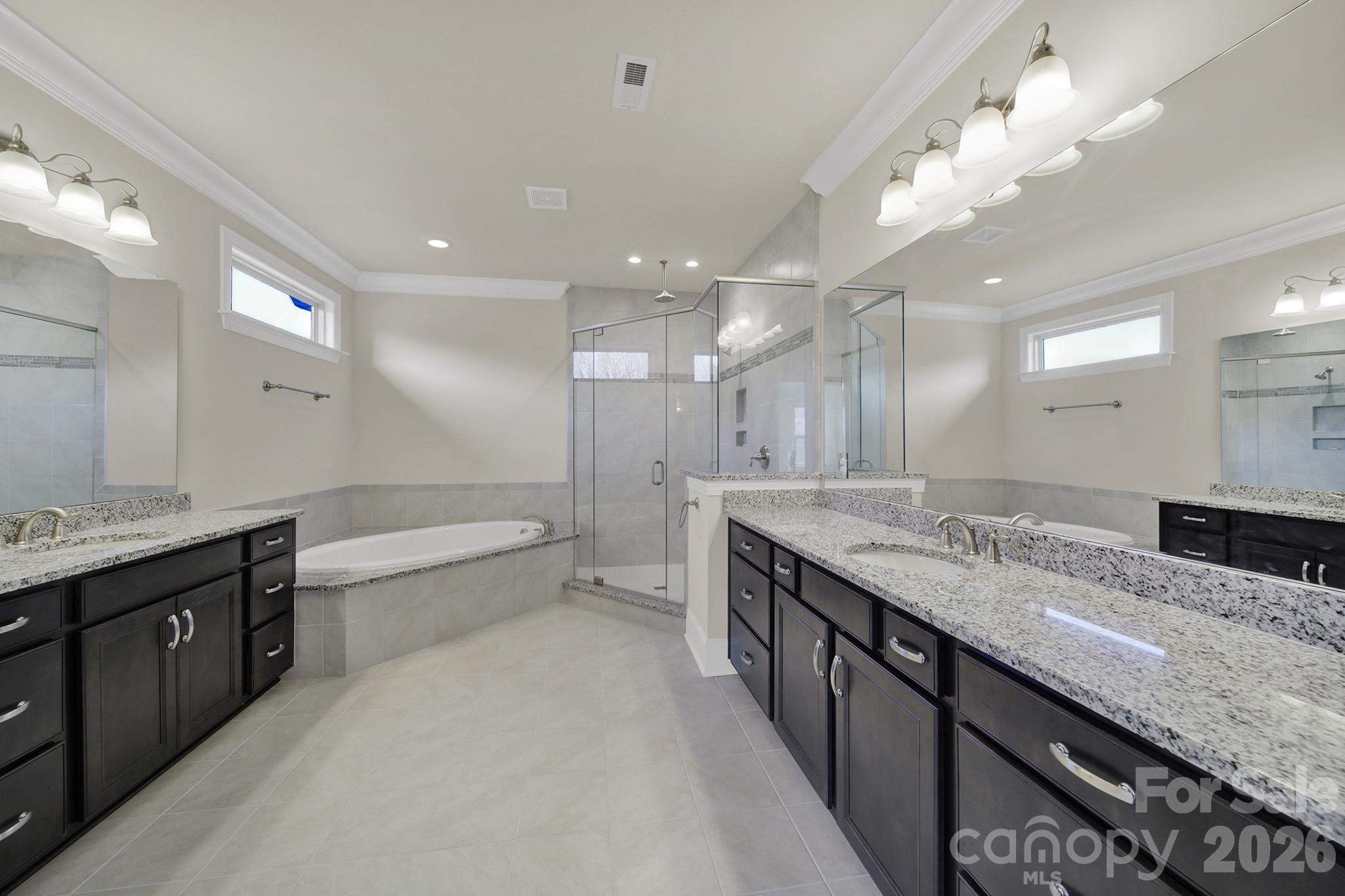 6507 Calvert Commons Drive Huntersville, NC 28078 - Photo 19 of 47 a large bathroom with a granite countertop double vanity sink a mirror and a bathtub