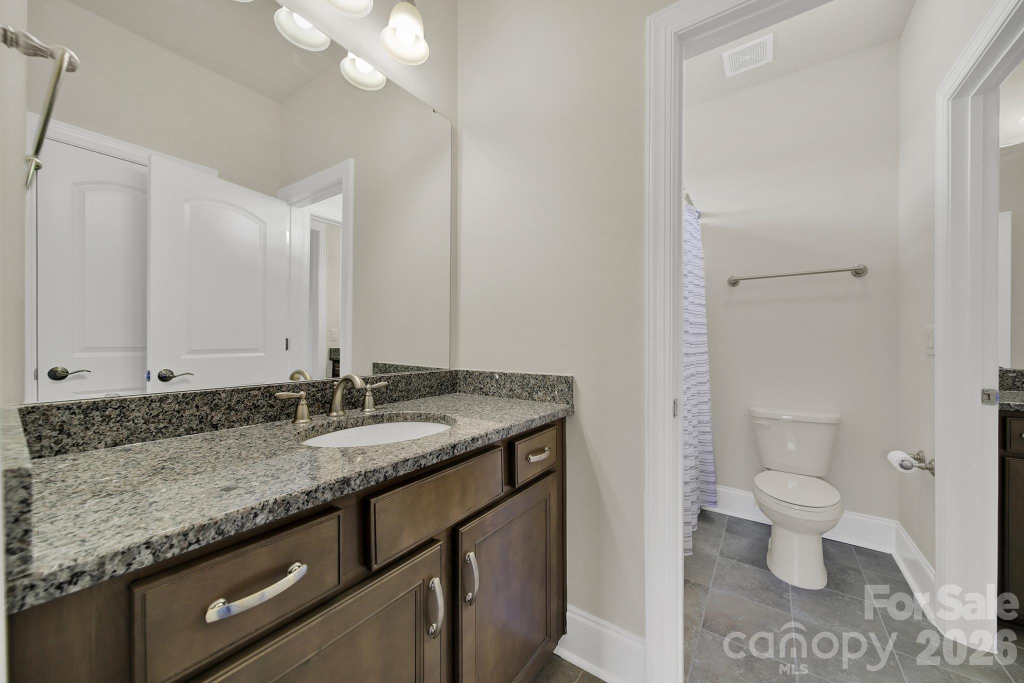 6507 Calvert Commons Drive Huntersville, NC 28078 - Photo 26 of 47 a bathroom with a granite countertop sink a toilet and a mirror