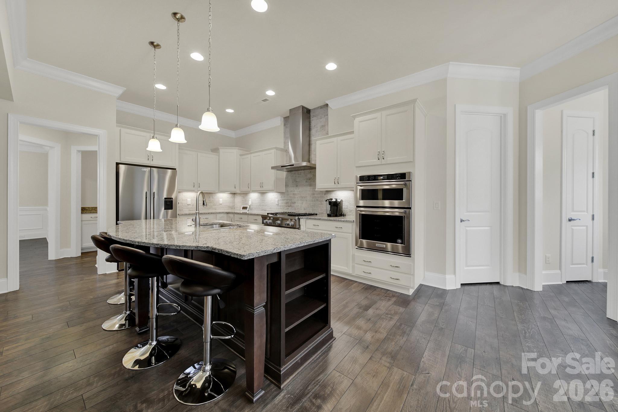 6507 Calvert Commons Drive Huntersville, NC 28078 - Photo 6 of 47 a kitchen with kitchen island a wooden floor and chairs