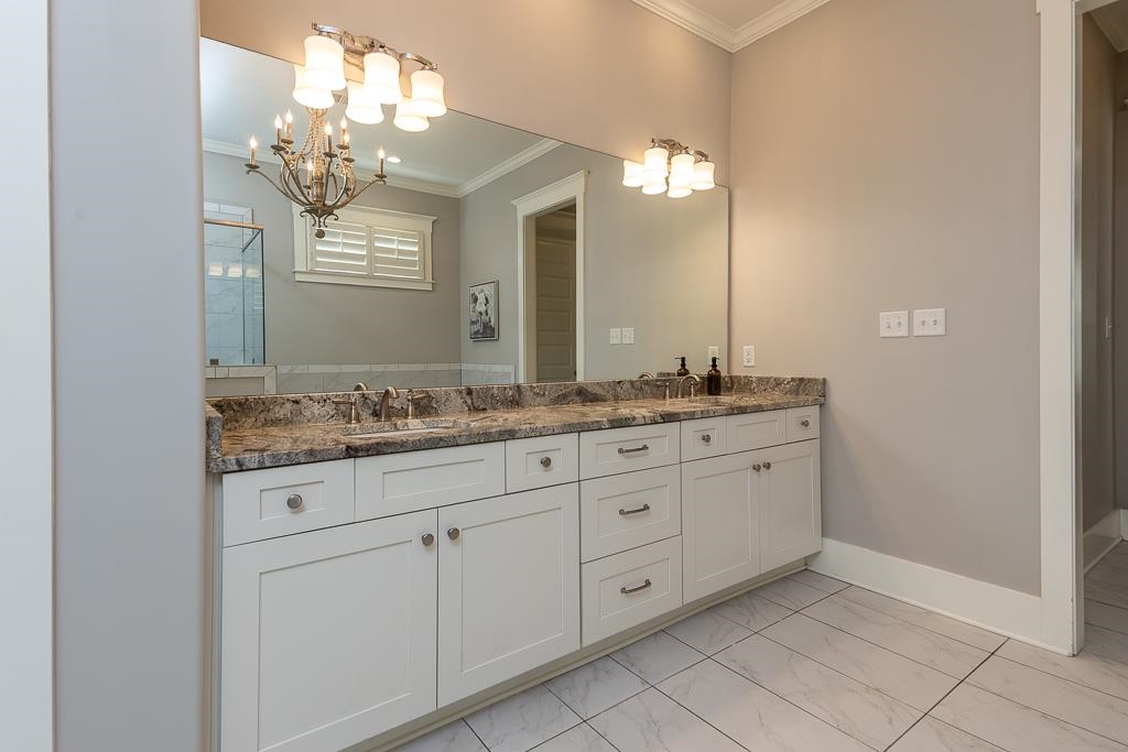 328 Washington Street Collierville, TN 38017 - Photo 16 of 33 Double vanity with white shaker cabinetry, stone countertop, dual sinks, and two wall-mounted light fixtures