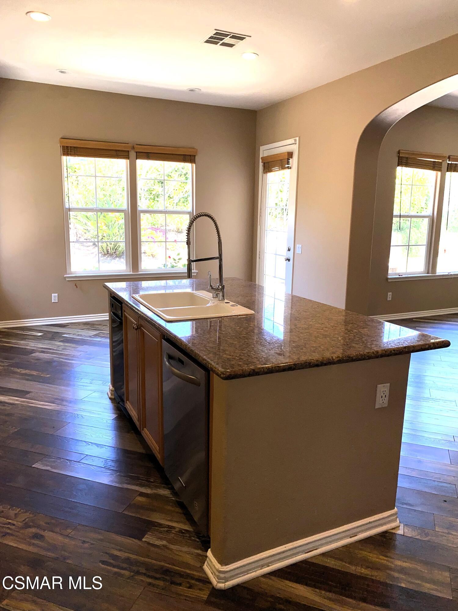 4501 Via Rio Newbury Park, CA 91320 - Photo 12 of 24 a kitchen with kitchen island granite countertop white cabinets and wooden floor