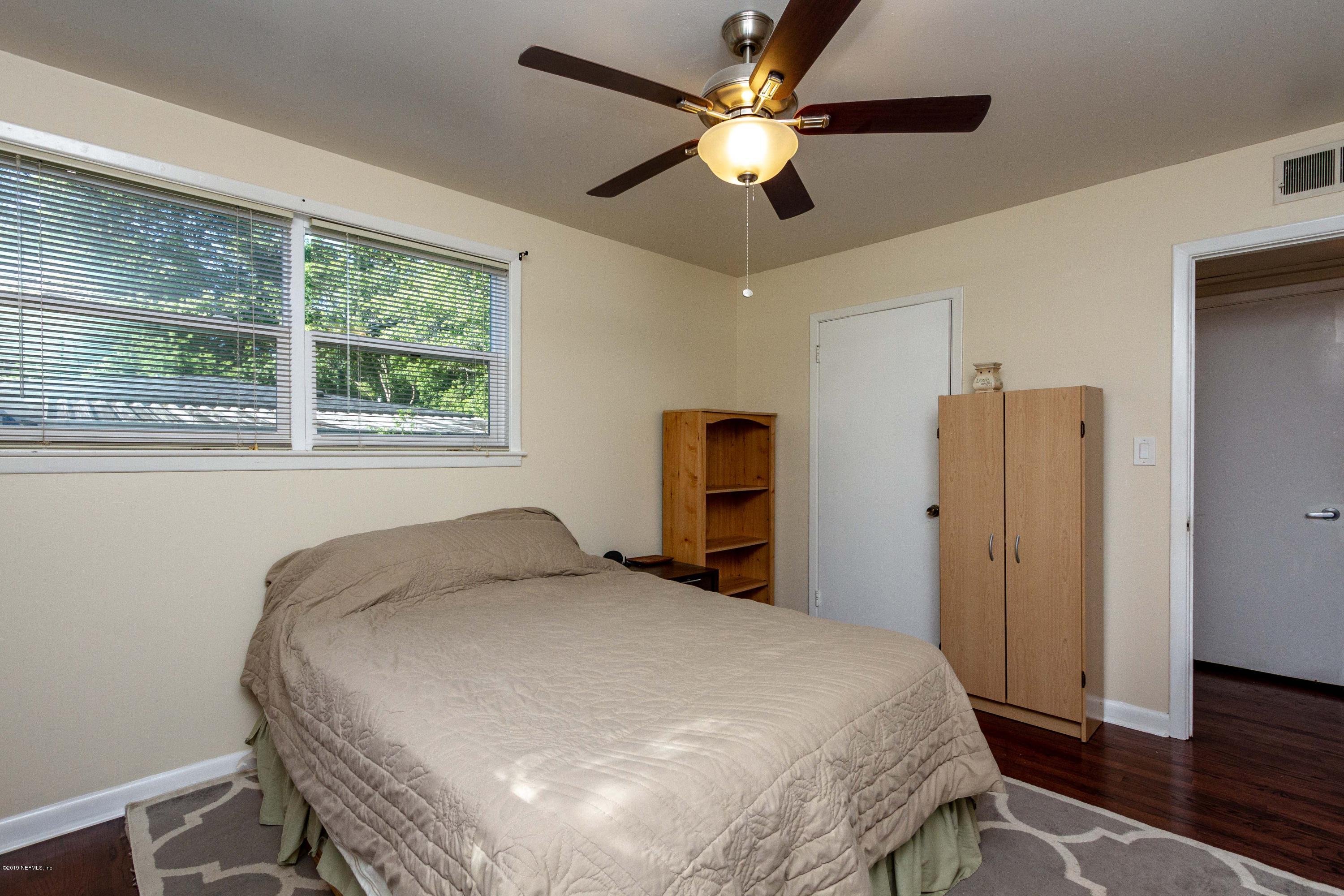 7420 Hennessy Road Jacksonville, FL 32244 - Photo 22 of 39 a bedroom with a bed and a chandelier