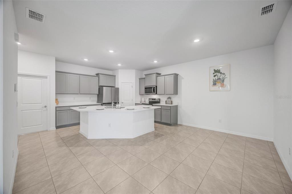2555 Bending Bonsai Drive Wesley Chapel, FL 33543 - Photo 40 of 59 a large white kitchen with kitchen island a stove a sink a refrigerator and white cabinets