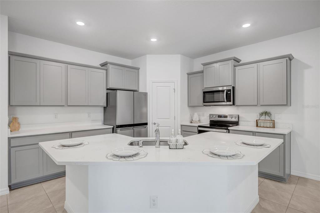 2555 Bending Bonsai Drive Wesley Chapel, FL 33543 - Photo 43 of 59 a kitchen with stainless steel appliances a sink a stove a microwave a center island and cabinets