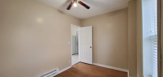 an empty room with a ceiling fan and wooden floor