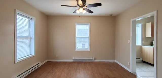 a view of an empty room with wooden floor and a window