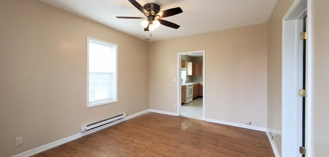 a view of empty room with wooden floor and fan