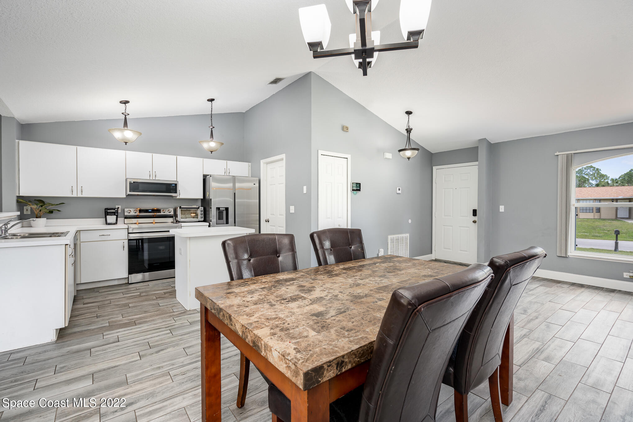 1290 Daton Road Southwest Palm Bay, FL 32908 - Photo 16 of 29 a large kitchen with kitchen island a stove a sink a refrigerator and white cabinets with wooden floor