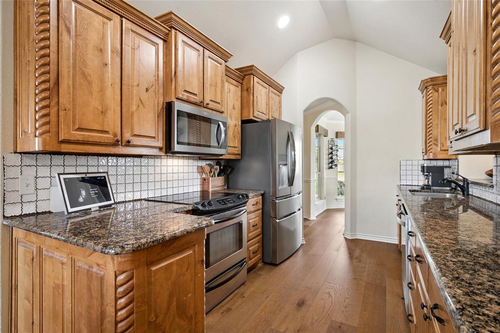 199 Newfield Lane Springtown, TX 76082 - Photo 13 of 38 The kitchen features wood cabinetry, granite countertops, a tile backsplash, and stainless steel appliances