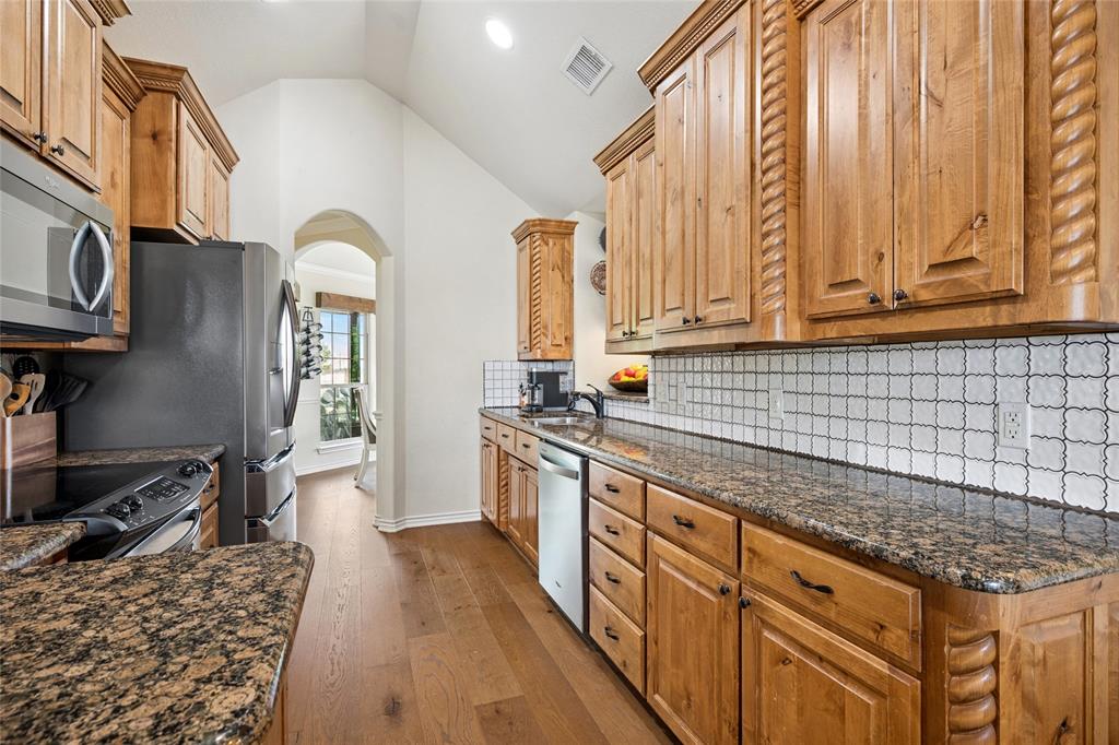 199 Newfield Lane Springtown, TX 76082 - Photo 14 of 38 The kitchen features wood cabinetry with carved details, granite countertops, and a decorative tile backsplash
