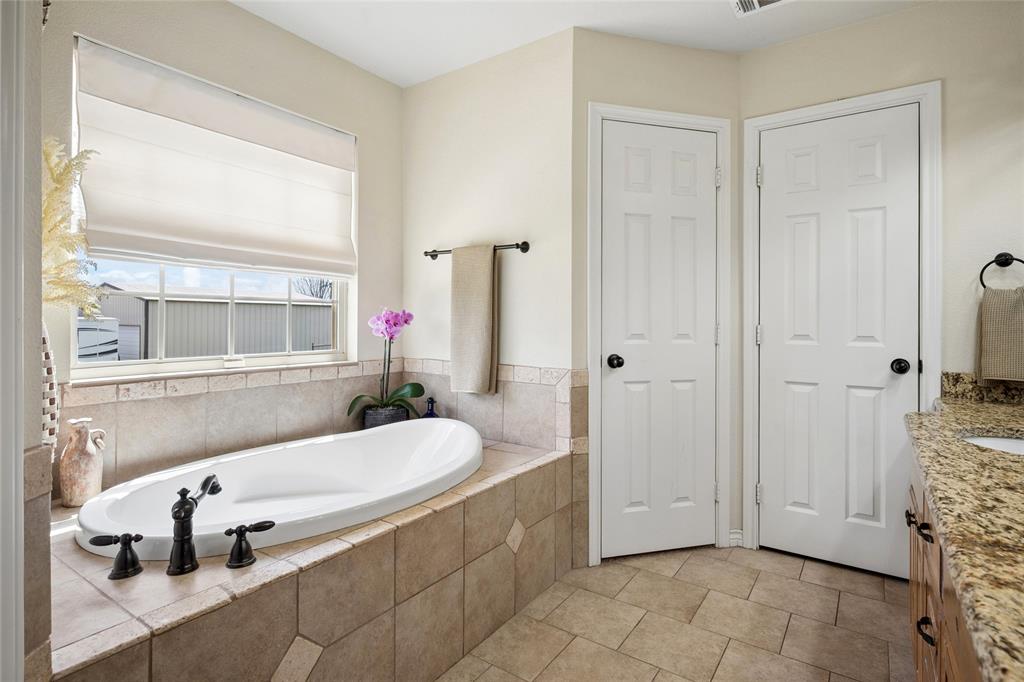 199 Newfield Lane Springtown, TX 76082 - Photo 22 of 38 This bathroom features a large soaking tub with a tiled surround, a window with a blind, and light-colored walls