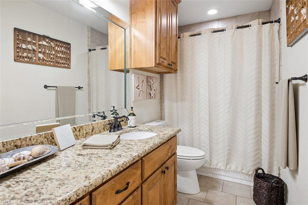 199 Newfield Lane Springtown, TX 76082 - Photo 25 of 38 The bathroom features a vanity with a light-colored granite countertop, a white sink, and wooden cabinetry