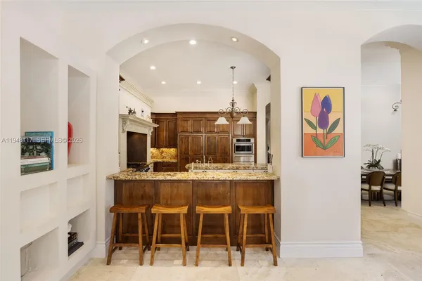 a dining hall with stainless steel appliances kitchen island granite countertop a dining table chairs and sink