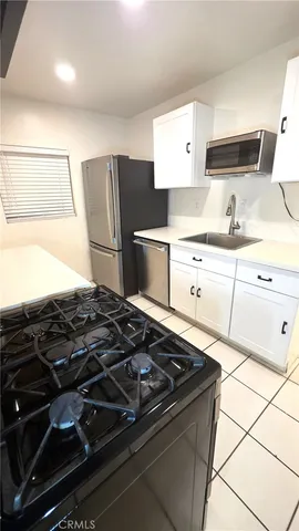 a kitchen with stainless steel appliances a sink a stove a microwave a counter top space and cabinets