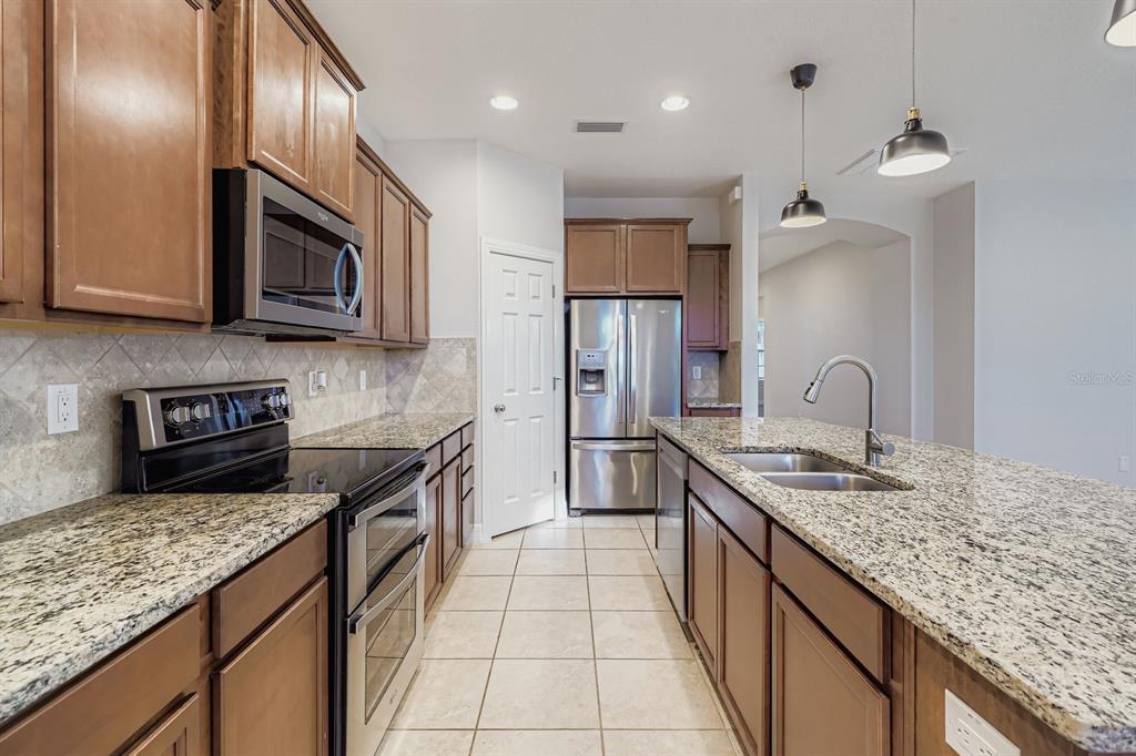 16355 Treasure Point Drive Wimauma, FL 33598 - Photo 12 of 28 a kitchen with stainless steel appliances granite countertop a sink stove and refrigerator