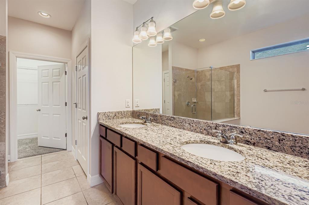 16355 Treasure Point Drive Wimauma, FL 33598 - Photo 17 of 28 a bathroom with a granite countertop sink a toilet a large mirror and shower