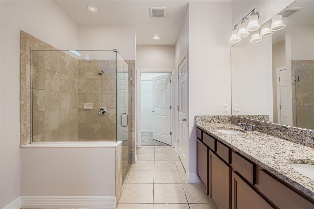 16355 Treasure Point Drive Wimauma, FL 33598 - Photo 18 of 28 a bathroom with a granite countertop sink a mirror and shower