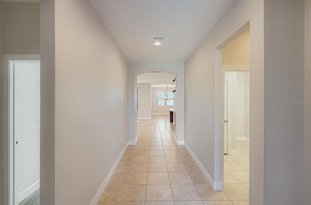 16355 Treasure Point Drive Wimauma, FL 33598 - Photo 6 of 28 a hallway with wooden floor windows and a bathroom