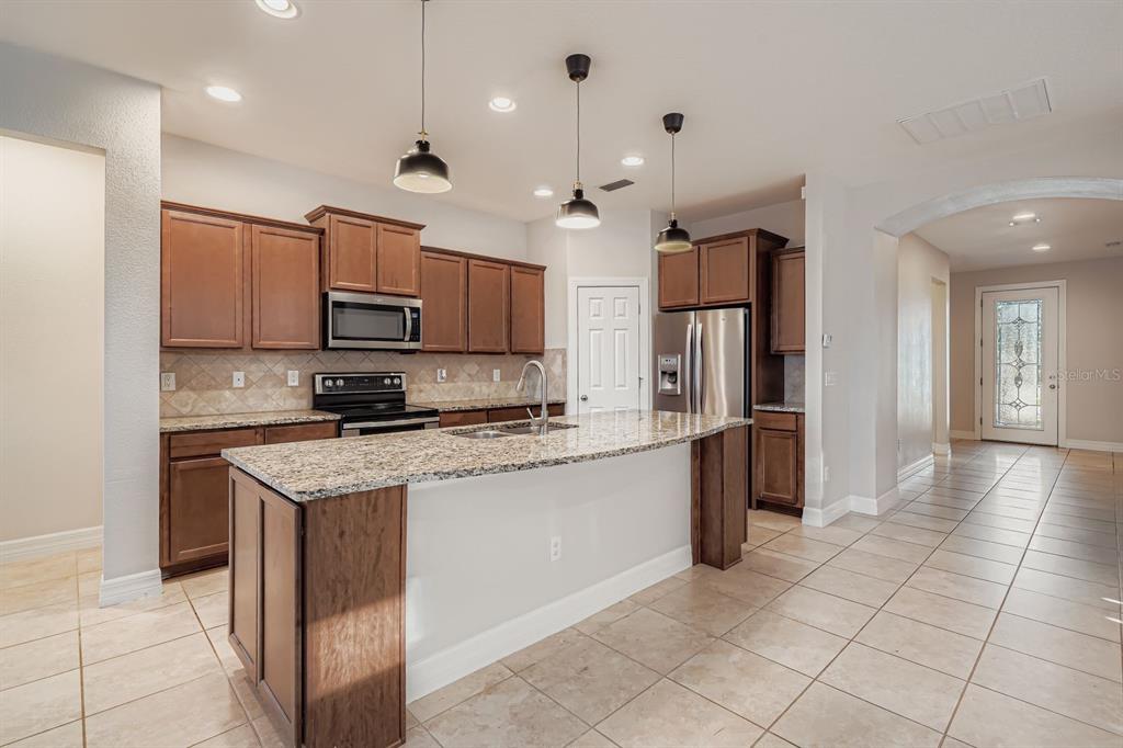 16355 Treasure Point Drive Wimauma, FL 33598 - Photo 8 of 28 a kitchen with stainless steel appliances granite countertop a refrigerator a stove a sink and a microwave