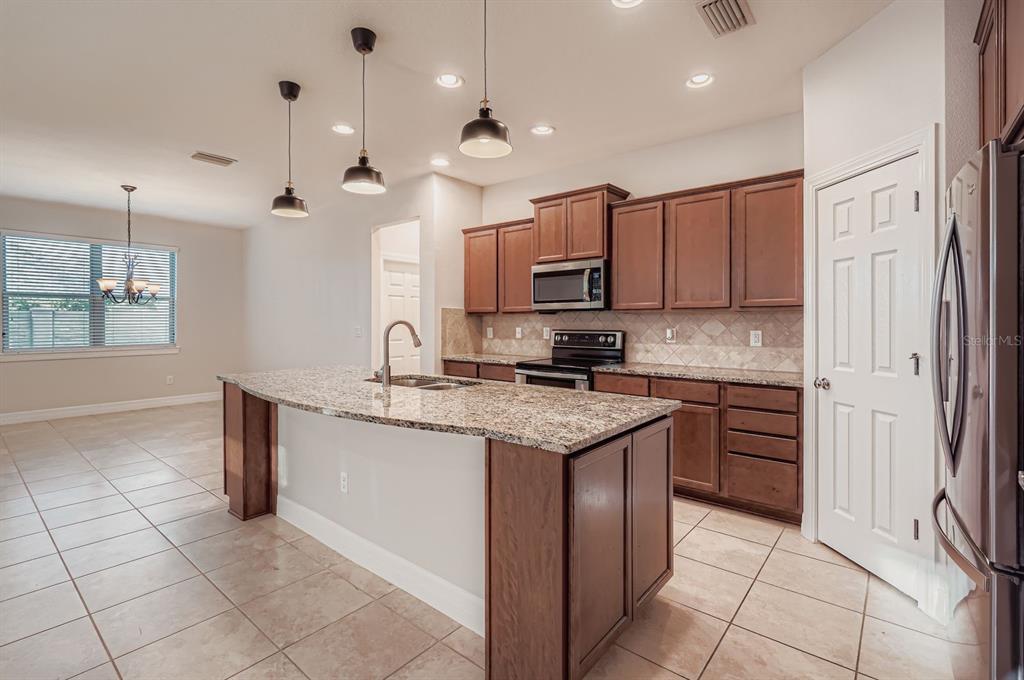 16355 Treasure Point Drive Wimauma, FL 33598 - Photo 9 of 28 a kitchen with kitchen island granite countertop a sink cabinets and stainless steel appliances