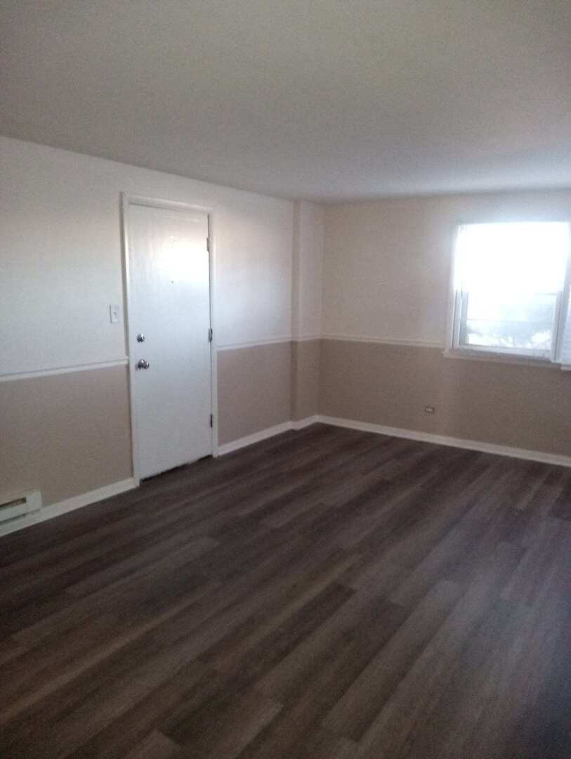 2915 West 79th Street, Unit G Chicago, IL 60652 - Photo 2 of 13 an empty room with wooden floor and windows