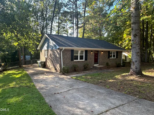 a view of a yard in front of a house with large tree