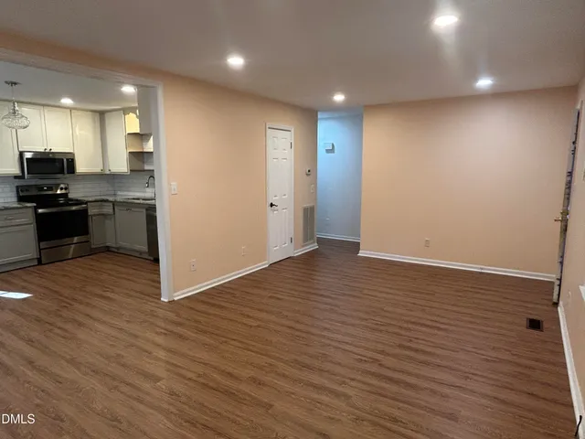 a view of kitchen with kitchen island wooden floor stainless steel appliances and cabinets