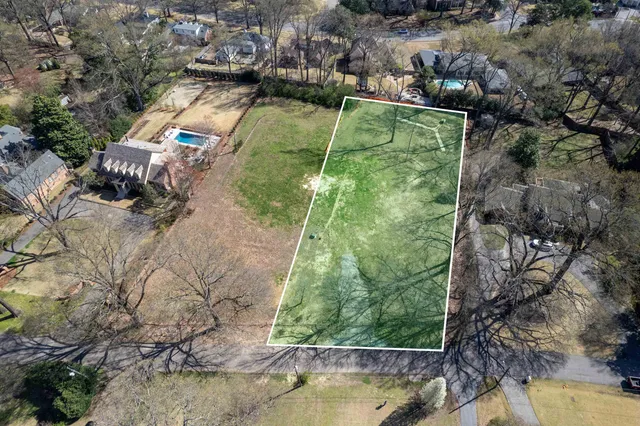an aerial view of a residential houses with outdoor space and trees