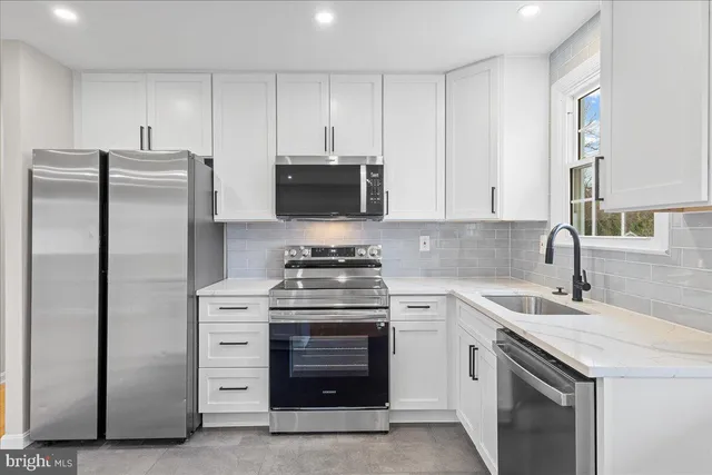 a kitchen with stainless steel appliances granite countertop a stove a refrigerator and a sink