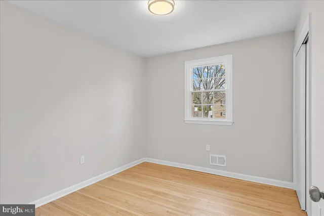 a view of an empty room with wooden floor and window