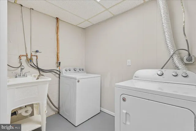a bathroom with a sink and a washing machine with a mirror