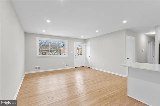 a view of empty room with wooden floor and window