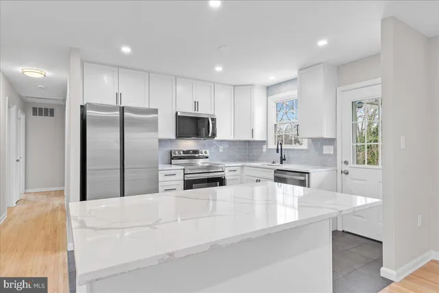 a kitchen with granite countertop a refrigerator a sink a stove a oven a dining table and chairs