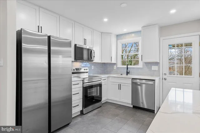 a kitchen with stainless steel appliances granite countertop a refrigerator a sink a stove a microwave and island