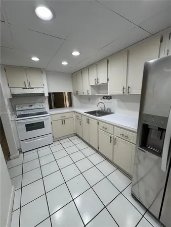a kitchen with a sink white cabinets and appliances